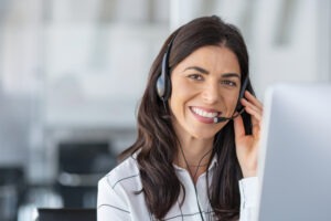 A woman smiles as she answers phone calls in Spanish for lawyers. Enlist our Spanish answering service for lawyers now.